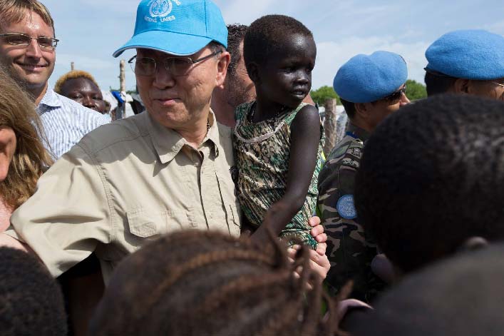 Ban Ki Moon with child in arms, greeting crowd.