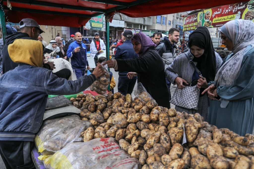 Palestinian refugees purchasing food during war
